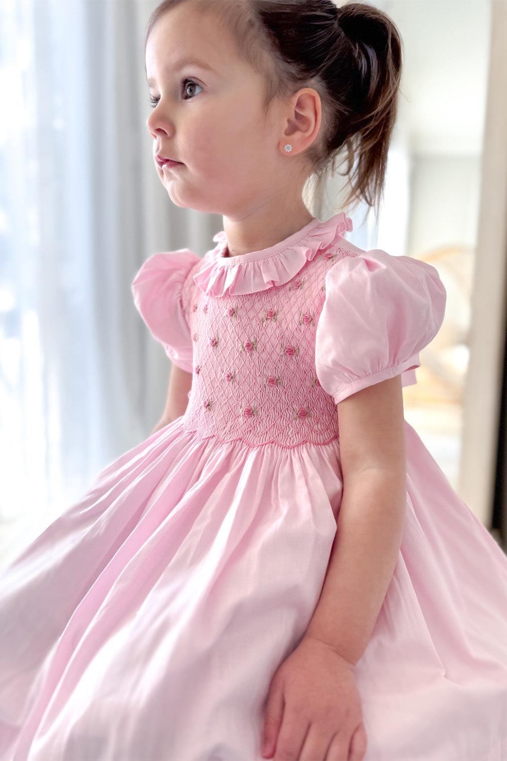 Girl wearing pink hand smocked dress with puff sleeve