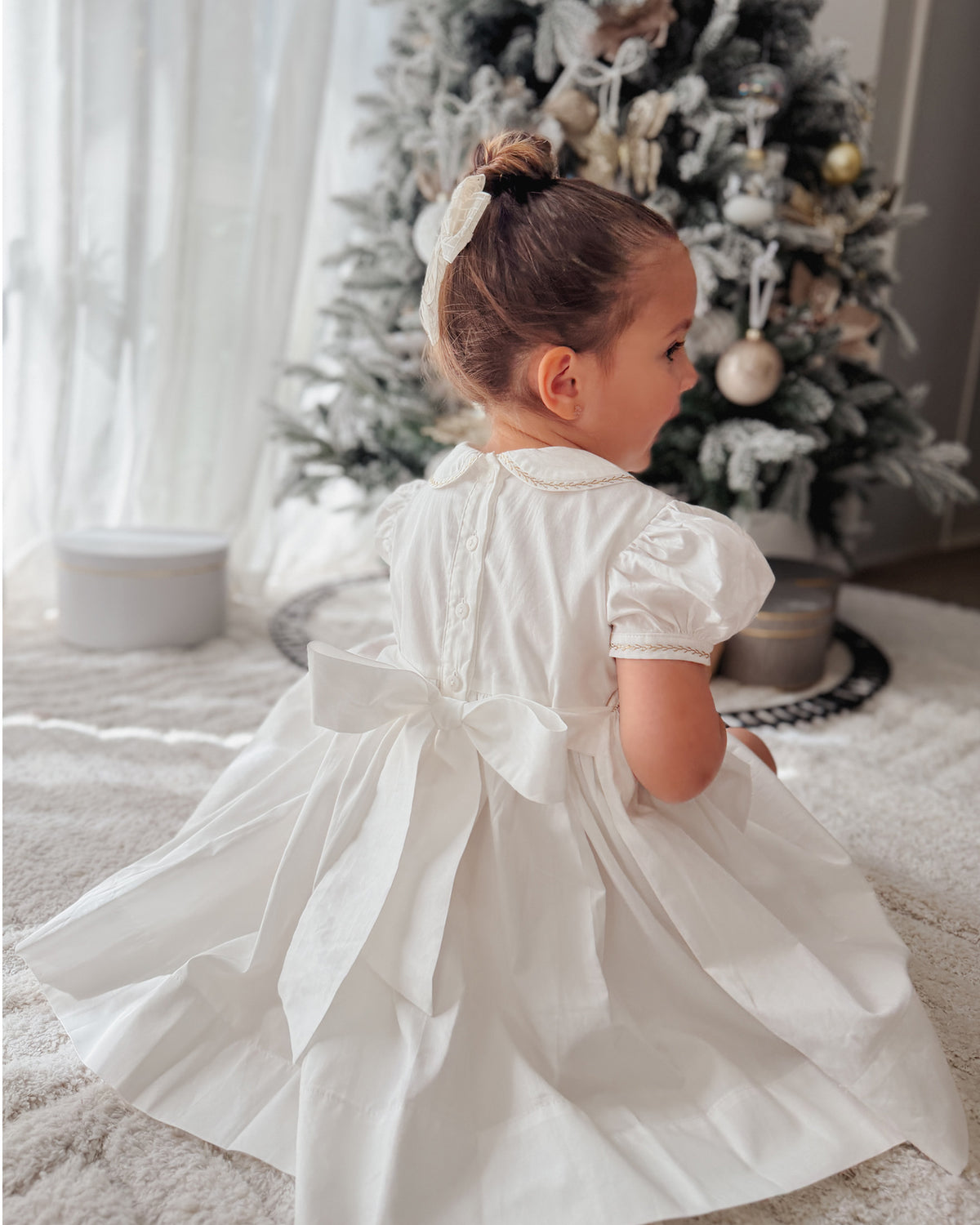Back view of off-white girls Christmas dress with sash bow and full gathered skirt