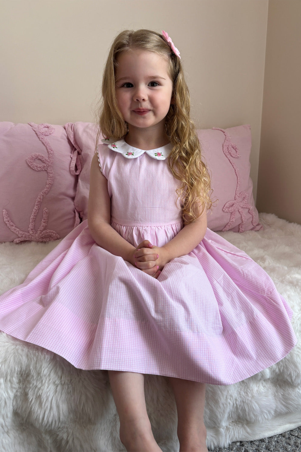 Girl in sleeveless pretty pink gingham dress with embroidered roses
